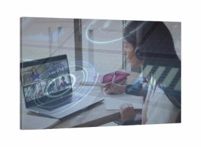 Writing student in sweater over-ear headphones at home desk, with laptop, notes, HUD, copy space