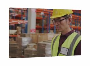 Checking Korean worker in yellow helmet and hi-vis vest inspecting racking at warehouse, copy space