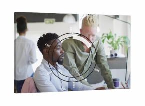 Collaborating coworkers wearing button-downs pointing at monitor in open office, with HUD overlay