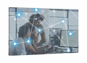 Working three coworkers in casual tops leaning in office, pointing at monitors and network overlay