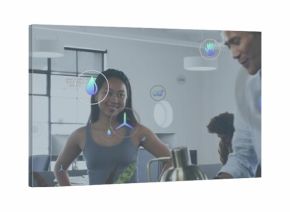 Standing woman in sleeveless grey top guiding team in open-plan office, with kettle and AR icons