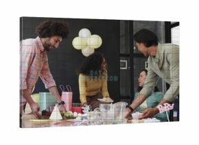 Gathering colleagues in casual business wear reaching across meeting table with cupcakes, gift bags