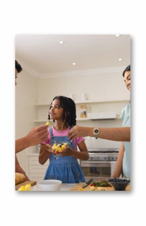 Family enjoying preparing healthy meal together in modern kitchen, sharing smiles