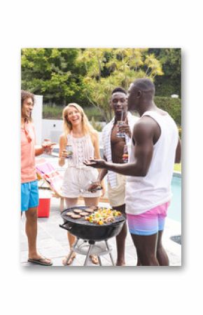 Diverse group of friends enjoying a barbecue by the pool, sharing laughter and drinks