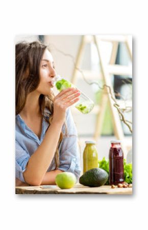 Beautiful woman sitting with drinks and healthy green food at home. Vegan meal and detox concept