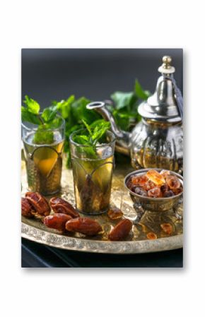 Moroccan mn tea in traditional glasses with mint, dates and sugar