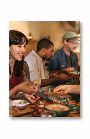 Smiling young friends enjoying dinner together in a trendy bistro