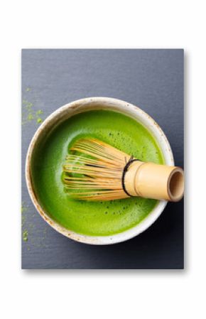 Matcha green tea cooking process in a bowl with bamboo whisk. Black slate background. Top view.