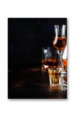Selection of hard alcoholic drinks in big glasses and small shot glass in assortent: vodka, rum, cognac, tequila, brandy and whiskey. Dark vintage background, selective focus, copy space