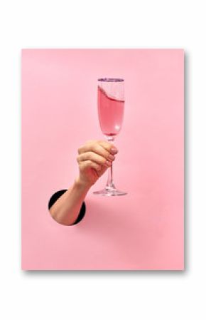 Kieliszek do wina różanego w kobiecej dłoni z dziury w ścianie.