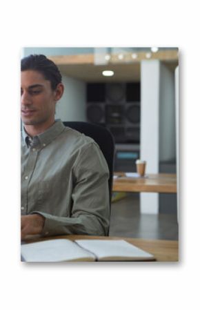 Middle Eastern man typing on laptop with notebook, coffee cup and speakers in office, copy space