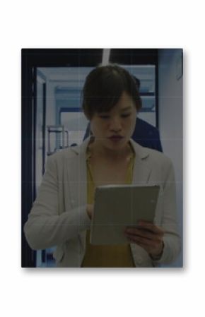 Holding tablet, Asian professional analyzing charts in office hallway with chart overlay and lights