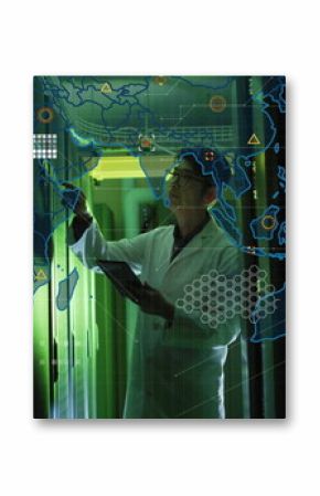 Reaching Korean engineer wearing lab coat holding tablet in green data center corridor, network map
