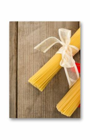 Raw spaghetti tied with ribbons on wooden table