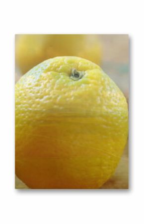 Displaying single orange showcasing textured rind on rustic wooden tabletop, with citrus leaves