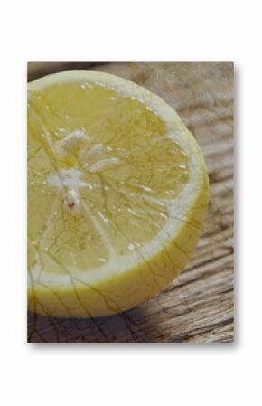 Resting halved lemon glistening on rustic wooden tabletop, revealing slender twig shadows