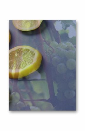 Displaying circular lemon slices layering at dark grey tabletop, green grape cluster, vine branches
