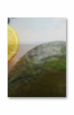 Displaying half-cut orange on glass countertop by window with avocado and blueberries, copy space