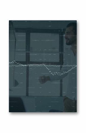 Gesturing man in white shirt presenting on dual monitors in office meeting, mic arm, copy space