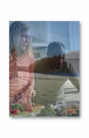 Chopping vegetables on wooden cutting board, couple preparing salad at kitchen island with laptop