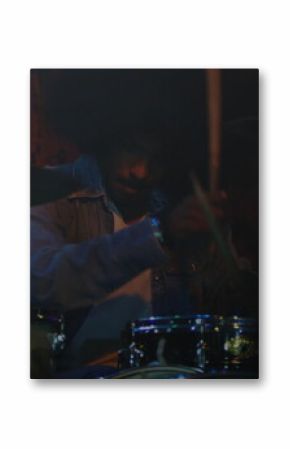 Playing Indian drummer hitting drums and cymbals on club stage, with denim jacket and drumsticks