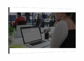 Typing developer examining code on laptop at open-plan office, with lamp and pencils, copy space