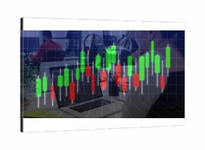 Displaying silver laptop projecting candlestick charts at office desk, with lamp and potted plant