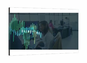 Holding printed report analyst wearing top sitting at office desk, with monitors displaying charts
