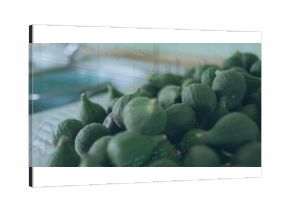 Showing cluster of green figs resting on cloth beside tray on countertop, with faint digital graphs