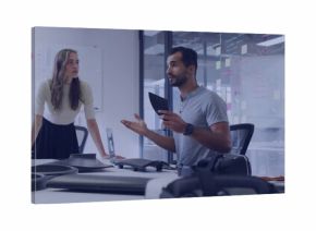 Presenting engineer holding tablet gesturing at drone prototypes in office with whiteboard sketches