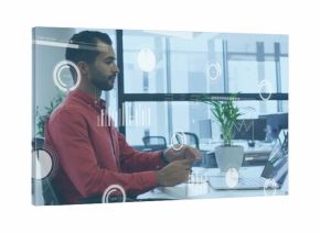 Office professional in red shirt typing on laptop and holding smartphone in office, copy space