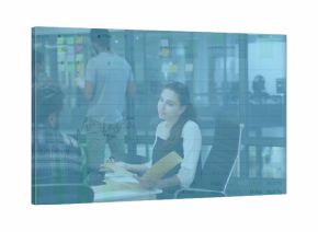 Collaborating office team discussing project at white table in workspace with sticky notes on glass