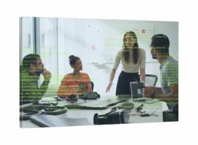 Leading standing woman wearing business casual guiding team in office with laptop VR headsets