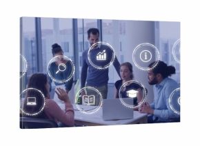 Discussing five staff wearing business-casual leaning around office table with laptop, papers