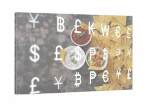 Displaying triangular tortilla chips and three bowls on dark tabletop, currency overlay, copy space