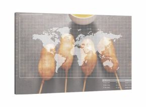 Showing four battered corn dogs on skewers on studio tabletop, with mustard bowl and map overlay