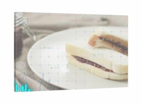 Displaying jam sandwich on ceramic plate on wooden table, with jam jar, napkin, overlay, copy space