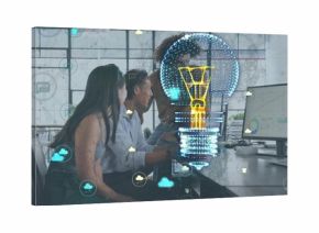 Reviewing charts, team in office wear leaning over monitors at office, hologram bulb and clouds