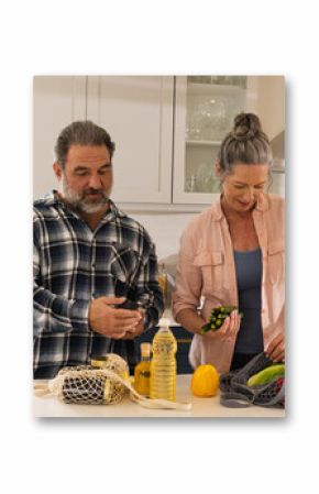 Mature couple unpacking groceries in kitchen, preparing healthy meal together, at home