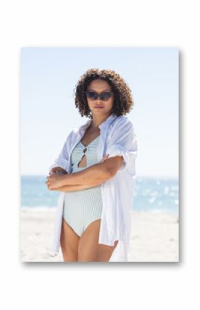 Young biracial woman stands confidently on the beach