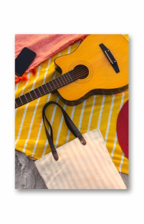 A guitar, hat, and smartphone rest on a beach blanket, with copy space