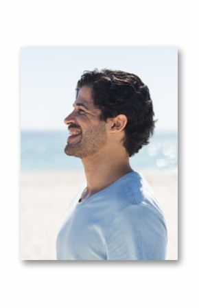 A young biracial man smiles brightly outdoors at the beach