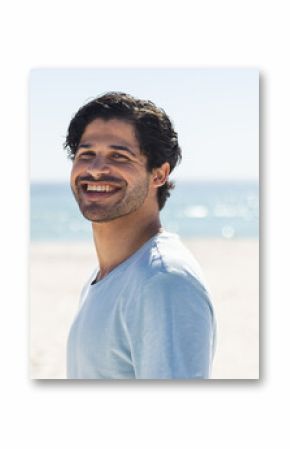 A young biracial man smiles brightly at the beach