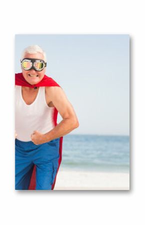 Red superhero-style cape fluttering at sandy beach edge, reflective goggles shining under clear sky
