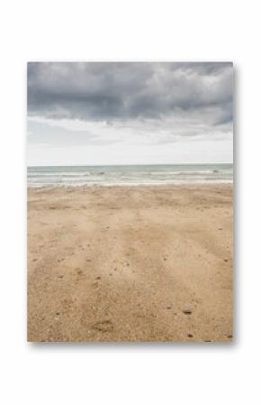 Flat design is showing beach with pebbles and shells meeting calm sea under dark clouds