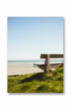 Empty bench by grass at beach