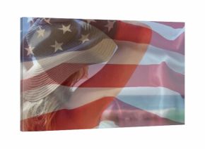 Raising bikini-clad female adjusting wide-brimmed sun hat on shore with ocean waves, flag overlay