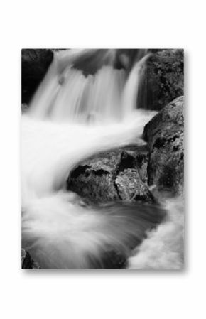 river rocks in smooth satin water flow of waterfall in black and white in long exposure