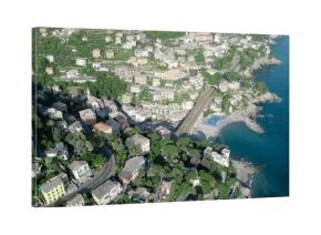 Capturing pastel buildings clustering on steep terraced hillside by rocky shore with blue umbrellas