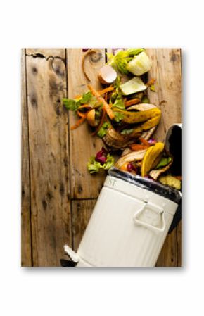 Vertical image of organic fruit and vegetable food waste spilling from open kitchen composting bin